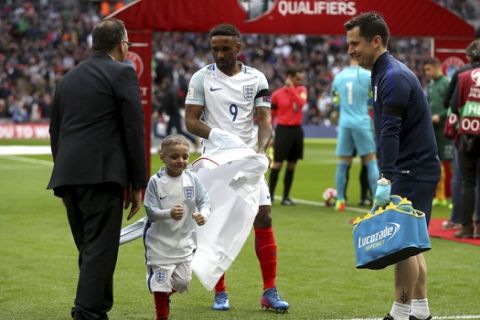 England's Jermain Defoe walks with mascot Bradley Lowery as he leaves the pitch before the World Cup Group F qualifying soccer match against Lithuania at Wembley Stadium, London Sunday March 26, 2017.  Bradley Lowery is battling a rare form of cancer and led England out onto the pitch at Wembley on March 26. (Adam Davy/PA via AP)