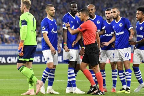 Schalke players argue with referee Jesus Gil Manzano after he decided on penalty during the Champions League group D soccer match between FC Schalke 04 and FC Porto at the Arena AufSchalke in Gelsenkirchen, Germany, Tuesday, Sept. 18, 2018. (AP Photo/Martin Meissner)