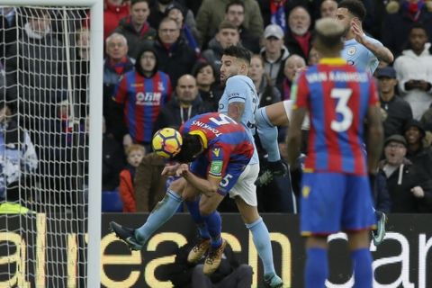 Crystal Palace's James Tomkins, centre,  attempts a header on goal during the English Premier League soccer match between Crystal Palace and Manchester City at Selhurst Park in London, Sunday Dec. 31, 2017. (AP Photo/Tim Ireland)
