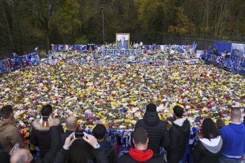 Fans observe floral tributes for those who lost their lives in the Leicester City helicopter crach including Leicester City Chairman Vichai Srivaddhanaprabha ahead of the Premier League match at the King Power Stadium, Leicester, England. Saturday Nov. 10, 2018. (Joe Giddens/PA via AP)