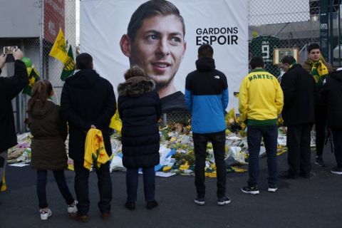 Nantes soccer team supporters stand in front of a poster of Argentinian player Emiliano Sala outside La Beaujoire stadium before the French soccer League One match Nantes against Saint Etienne, in Nantes, western France, Wednesday, Jan.30, 2019. Sala disappeared over the English Channel on Jan. 21, 2019 as it flew from France to Wales. Sala had just been signed by Premier League club Cardiff. (AP Photo/Thibault Camus)