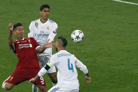 Liverpool's Roberto Firmino, left, challenges for the ball with Real Madrid's Sergio Ramos, right, and Raphael Varane during the Champions League Final soccer match between Real Madrid and Liverpool at the Olimpiyskiy Stadium in Kiev, Ukraine, Saturday, May 26, 2018. (AP Photo/Darko Vojinovic)