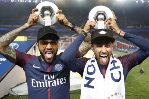 PSG players Neymar, right, and Dani Alves hold their League One winners trophy after the soccer match between Paris Saint-Germain and Stade Rennais at the Parc des Princes stadium in Paris, Saturday May 12, 2018. (AP Photo/Christophe Ena)
