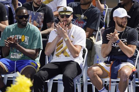 From left, Golden State Warriors' Draymond Green, Klay Thompson and Stephen Curry clap on stage before the start of their NBA championship parade in San Francisco, Monday, June 20, 2022. (AP Photo/Eric Risberg)