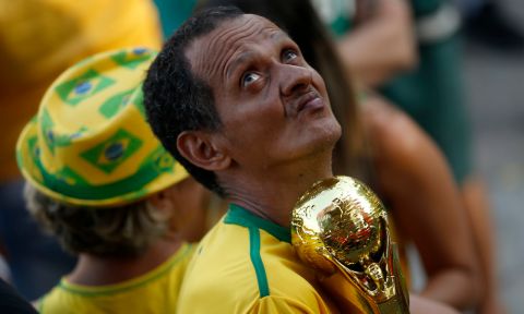 A Brazil soccer fan holds a replica of the World Cup trophy during a live telecast of the Brazil vs. Belgium World Cup quarter finals soccer match, in Rio de Janeiro, Brazil, Friday, July 6, 2018. (AP Photo/Silvia Izquierdo)