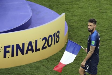 France's Olivier Giroud carries a French flag celebrating at the end of the final match between France and Croatia at the 2018 soccer World Cup in the Luzhniki Stadium in Moscow, Russia, Sunday, July 15, 2018. (AP Photo/Thanassis Stavrakis)