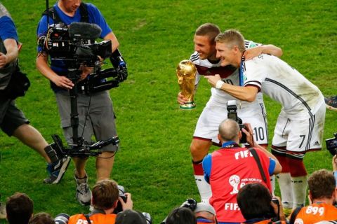 RIO DE JANEIRO, BRAZIL - JULY 13:  Lukas Podolski and Bastian Schweinsteiger of Germany celebrate with the World Cup trophy after defeating Argentina 1-0 in extra time in the 2014 FIFA World Cup Brazil Final match between Germany and Argentina at Maracana on July 13, 2014 in Rio de Janeiro, Brazil.  (Photo by Jamie Squire/Getty Images)