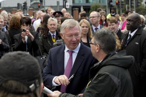 Manchester United's former manager Alex Ferguson, centre, signs autographs after unveiling a street sign named in his honour near Old Trafford Stadium, Manchester, England, Monday Oct. 14, 2013. Earlier in the day the side's manager for over 26 years was awarded the Honorary Freedom of the Borough of Trafford. (AP Photo/Jon Super)
