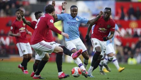 Manchester City's Raheem Sterling, center, fights for the ball during the English Premier League soccer match between Manchester United and Manchester City at Old Trafford in Manchester, England, Sunday, March 8, 2020. (AP Photo/Dave Thompson)