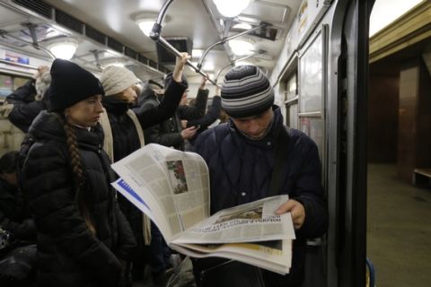 Man reads a newspaper at a metro station, in Kiev, Ukraine, Thursday, Feb. 12, 2015. Leaders of Russia, Ukraine, France and Germany on Thursday emerged from marathon 16-hour talks to announce a comprehensive peace deal for eastern Ukraine, but questions remained whether Ukraine and the pro-Russian rebels have agreed on all of its terms. (AP Photo/Sergei Chuzavkov)