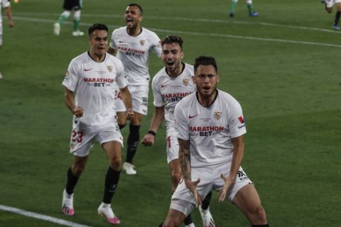 Sevilla's Lucas Ocampos, foreground, celebrates after scoring against Betis during their Spanish La Liga soccer match in Seville, Spain, Thursday, June 11, 2020. With virtual crowds, daily matches and lots of testing for the coronavirus, soccer is coming back to Spain. The Spanish league resumes this week more than three months after it was suspended because of the pandemic, becoming the second top league to restart in Europe. The Bundesliga was first. The Premier League and the Italian league should be next in the coming weeks. (AP Photo)