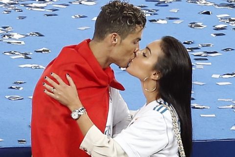 Real Madrid's Cristiano Ronaldo, left, is kissed by his girlfriend Georgina Rodriguez after winning the Champions League Final soccer match between Real Madrid and Liverpool at the Olimpiyskiy Stadium in Kiev, Ukraine, Saturday, May 26, 2018. Madrid defeated Liverpool by 3-1. (AP Photo/Darko Vojinovic)