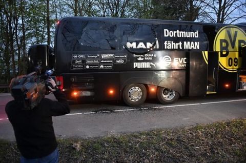 A camera man films Dortmund's team bus after it was damaged in an explosion before the Champions League quarterfinal soccer match between Borussia Dortmund and AS Monaco in Dortmund, western Germany, Tuesday, April 11, 2017.  (AP Photo/Martin Meissner)