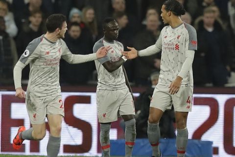 Liverpool's Sadio Mane, centre, celebrates with Liverpool's Andrew Robertson, left, and Liverpool's Virgil van Dijk after scoring his side's first goal during the English Premier League soccer match between West Ham United and Liverpool at the London Stadium in London, Monday, Feb. 4, 2019.(AP Photo/Kirsty Wigglesworth)