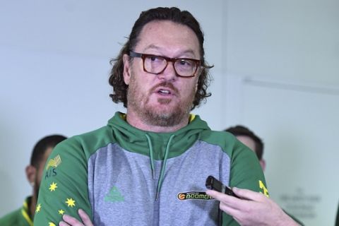 In this July 4, 2018, photo, Australia assistant coach and former NBA star Luc Longley speaks to the media as he arrives at Brisbane airport, after the violence that marred a World Cup qualifying match between the teams on Monday. Longley describes the bench-clearing brawl which saw 13 players, including four Australians, ejected from the match as the worst thing he had seen on a basketball court. (Dan Peled/AAP Image via AP)