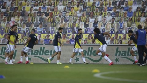 Fenerbahce's players warm up in front of cardboards with photographs of Fenerbahce fans on the stands during a Turkish Super League soccer match between Fenerbahce and Kayserispor in Istanbul, Friday, June 12, 2020. The Turkish Super Lig resumed its season on Friday without spectators after it had suspended games since March 20 due to the coronavirus pandemic, later than many other European leagues. (Erdem Sahin/Pool via AP)