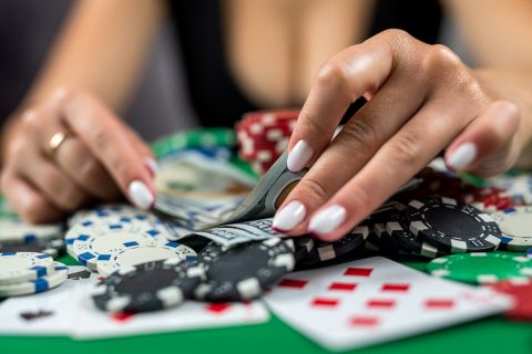 beautiful player woman counts chips for money and raises bet while playing poker in casino. gambling concept. a woman in a dress in a casino
