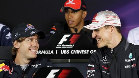 Red Bull Formula One driver Sebastian Vettel of Germany, left, and Mercedes Formula One driver Michael Schumacher of Germany, right,  chat as McLaren Formula One driver Lewis Hamilton of Britain, top, answers questions from a journalist during the press conference of the Chinese Formula One Grand Prix at the Shanghai International Circuit in Shanghai, China, Thursday, April 14, 201. (AP Photo/Eugene Hoshiko)