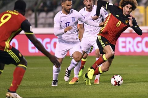Belgium's Marouane Fellaini, right, is chased by Greece's Panagiotis Tachtsidis, center, during the Euro 2018 Group H qualifying match between Belgium and Greece at the King Baudouin stadium in Brussels on Saturday, March 25, 2017. (AP Photo/Geert Vanden Wijngaert)
