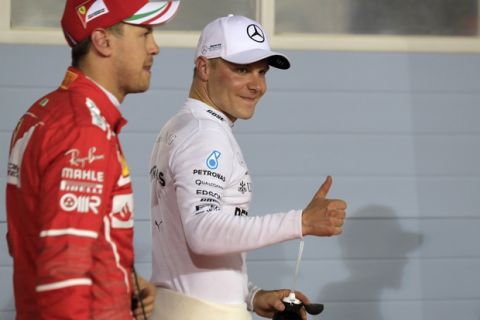 Mercedes driver Valtteri Bottas of Finland gestures after he clocked the fastest time during the qualifying session for the Bahrain Formula One Grand Prix, at the Formula One Bahrain International Circuit in Sakhir, Bahrain, Saturday, April 15, 2017. The Bahrain Formula One Grand Prix will take place on Sunday. At left is Ferrari driver Sebastian Vettel of Germany who clocked the third fastest time. (AP Photo/Hassan Ammar)