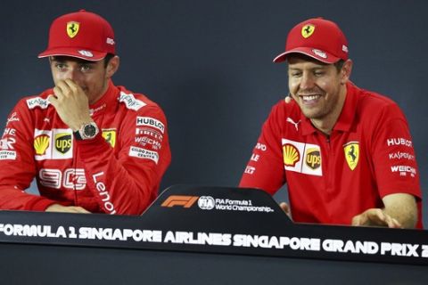 Ferrari driver Sebastian Vettel, right, of Germany jokes with Ferrari driver Charles Leclerc of Monaco at a press conference following his Singapore Formula One Grand Prix win at the Marina Bay City Circuit in Singapore, Sunday, Sept. 22, 2019. (AP Photo/Yong Teck Lim)