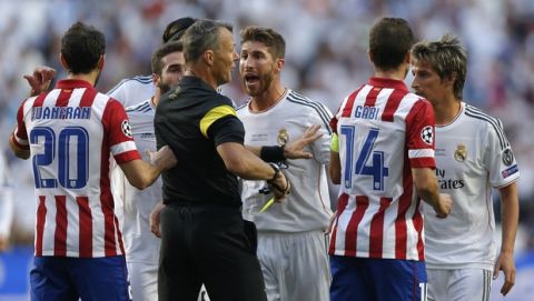 Real's Sergio Ramos, background centre is given a yellow card by referee Bjorn Kuipers,  during the Champions League final soccer match between Atletico de Madrid and Real Madrid, at the Luz stadium, in Lisbon, Portugal, Saturday, May 24, 2014. (AP Photo/Daniel Ochoa de Olza)