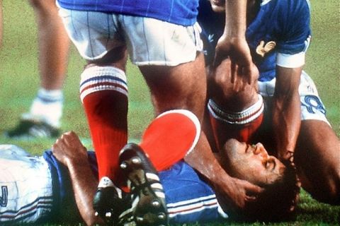 SEVILLA, SPAIN - JULY 8:  French defender Patrick Battiston lies on the ground as midfielder Michel Platini (10) and forward Didier Six surround him while waiting for the medical staff to come in 08 July 1982 in Sevilla during the World Cup semifinal soccer match between West Germany and France. West German goalkeeper Harald Schumacher charged into Battiston as he was going for the ball but was not thrown out by Dutch referee Charles Corver. West Germany beat France 5-4 on penalty kicks (1-1 at the end of regulation time; 3-3 at the end of extra time).  AFP PHOTO  (Photo credit should read STAFF/AFP/Getty Images)