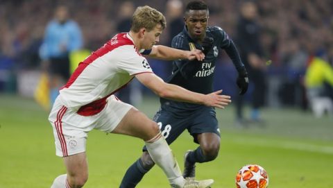 Ajax's Matthijs de Ligt, left, fights for the ball with Real forward Vinicius Junior during the first leg, round of sixteen, Champions League soccer match between Ajax and Real Madrid at the Johan Cruyff ArenA in Amsterdam, Netherlands, Wednesday Feb. 13, 2019. (AP Photo/Peter Dejong)