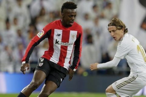 Athletic Bilbao's Inaki Williams, left, and Real Madrid's Luka Modric fight for the ball during a Spanish La Liga soccer match between Real Madrid and Athletic Bilbao at the Santiago Bernabeu stadium in Madrid, Spain, Sunday Dec. 22, 2019. (AP Photo/Paul White)