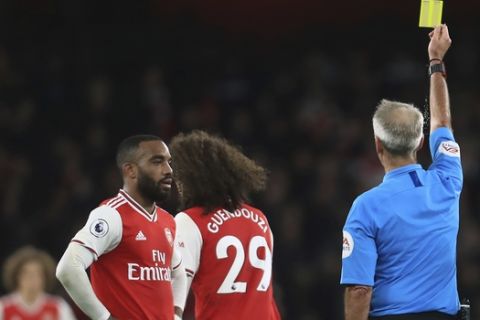 Referee Martin Atkinson, right, shows a yellow card to Arsenal's Matteo Guendouzi, second right, during the English Premier League soccer match between Arsenal and Crystal Palace at the Emirates stadium in London, Sunday, Oct. 27, 2019. (AP Photo/Leila Coker)