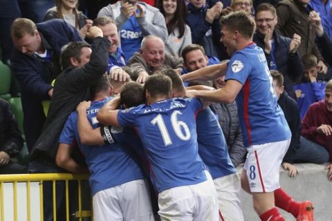 Linfield's Jordan Stewart is surrounded by his teammates as he celebrates scoring his side's first goal of the game during the Champions League Qualifying match between Linfield and La Fiorita at Windsor Park, Belfast, Northern Ireland, Wednesday June 28, 2017. (Niall Carson/PA via AP)