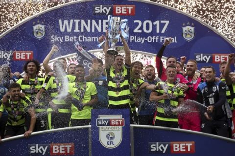 Huddersfield Town's Mark Hudson lifts the trophy after winning the Sky Bet Championship play-off final at Wembley Stadium, London, Monday, May 29, 2017. Huddersfield Town will play in England's top division for the first time in 45 years after beating Reading 4-3 in a penalty shootout on Monday in the League Championship playoff final, world soccer's richest single game worth a minimum $220 million. (Nick Potts/PA via AP)