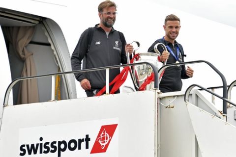 Liverpool soccer team manager Jurgen Klopp, left, and Jordan Henderson hold the Champions League Trophy as they arrive back to John Lennon Airport in Liverpool, England, Sunday June 2, 2019.  Liverpool is champion of Europe for a sixth time after beating Tottenham 2-0 in the Champions League final in Madrid Saturday. (Dave Howarth/PA via AP)