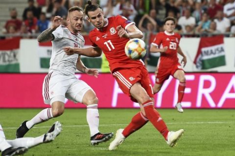 Wales' Gareth Bale tries to keep the control of the ball against a Hungary player during the UEFA Euro 2020 qualifying, Group E, soccer match at the Groupama Arena in Budapest, Hungary, Tuesday, June 11, 2019. (Joe Giddens/PA via AP)