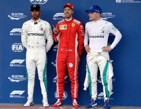Mercedes driver Lewis Hamilton of Britain, Ferrari driver Sebastian Vettel of Germany and Mercedes driver Valtteri Bottas of Finland, from left to right, pose for photos at the end of the qualifying session at the Baku Formula One city circuit, in Baku, Azerbaijan, Saturday, April 28, 2018. The Formula One race will be held on Sunday. Vettel clocked the fastest time, Hamilton was second and Bottas third. (AP Photo/Luca Bruno)