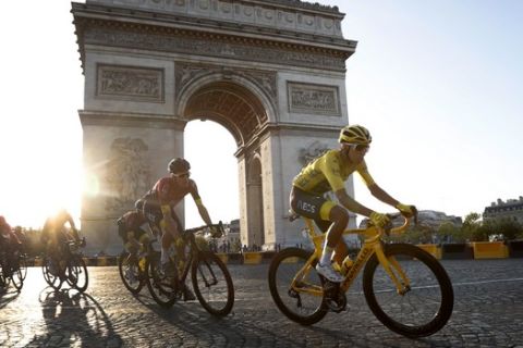 Colombia's Egan Bernal wearing the overall leader's yellow jersey, center, rides past the Arc de Triomphe on the Champs-Elysees during the twenty-first stage of the Tour de France cycling race over 128 kilometers (79.53miles) with start in Rambouillet and finish in Paris, France, Sunday, July 28, 2019. (AP Photo/Thibault Camus)