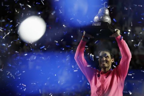 Spain's Rafael Nadal hoists his trophy as confetti falls, after he defeated Taylor Fritz, of the United States, 6-3, 6-2 in the men's final of the Mexican Open tennis tournament in Acapulco, Mexico, Saturday, Feb. 29, 2020. (AP Photo/Rebecca Blackwell)