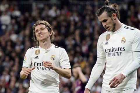 Real midfielder Luka Modric, left, and Real midfielder Gareth Bale react during the Spanish La Liga soccer match between Real Madrid and FC Barcelona at the Bernabeu stadium in Madrid, Saturday, March 2, 2019. (AP Photo/Andrea Comas)