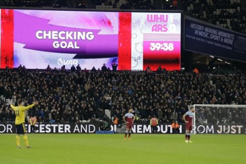 The big screen displays Checking Goal during a VAR review after West Ham's Angelo Ogbonna scoring his side's opening goal during the English Premier League soccer match between West Ham Utd and Arsenal at the London Stadium in London, Monday, Dec. 9, 2019. (AP Photo/Kirsty Wigglesworth)