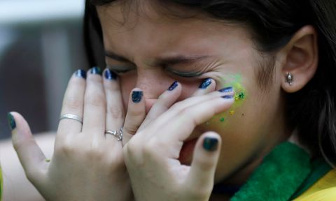 A Brazil soccer fan wipes tears from her eyes at the end of a live broadcast of the World Cup quarterfinal match between Brazil and Belgium in Rio de Janeiro, Brazil, Friday, July 6, 2018. Belgium knocked Brazil out of the World Cup and advanced to the semi-finals.  (AP Photo/Leo Correa)