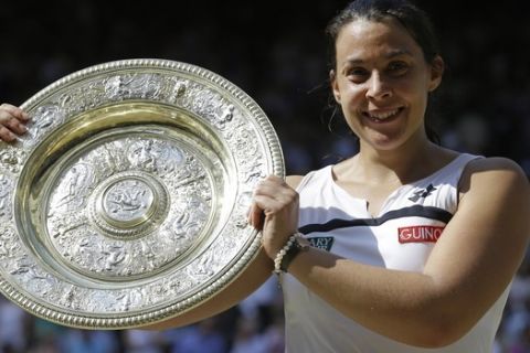 FILE - A  Saturday, July 6, 2013 file photo showing Marion Bartoli of France smiling as she holds the trophy after winning the Women's singles final match against Sabine Lisicki of Germany at the All England Lawn Tennis Championships in Wimbledon, London. Three years after winning the title at Wimbledon, Marion Bartoli said she has contracted an unknown virus and her life is an "absolute nightmare." The 31-year-old Frenchwoman is now extremely thin and said it's because she is ill. (AP Photo/Anja Niedringhaus, File)