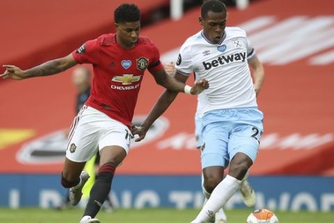Manchester United's Marcus Rashford, left, vie for the ball with West Ham's Issa Diop the English Premier League soccer match between Manchester United and West Ham at the Old Trafford stadium in Manchester, England, Wednesday, July 22, 2020. (Martin Rickett/Pool via AP)