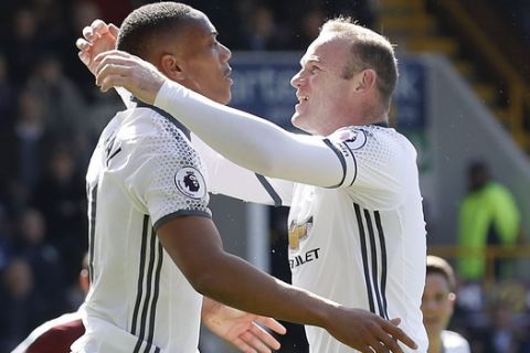 Manchester United's Anthony Martial, left, celebrates scoring his side's first goal of the game against Burnely, with Wayne Rooney, right, during their English Premier League soccer match at Turf Moor in Burnley, England, Sunday April 23, 2017. (Martin Rickett/PA via AP)