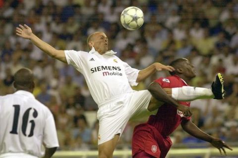 Real Madrid's Argentine player Esteban Cambiasso, left leaps for a high ball as Liverpool's Emile Heskey holds onto his leg during the first match in the Centenary Trophy Tournament in Madrid's Bernabeu stadium, Spain Friday Aug. 2, 2002. (AP Photo/Paul White)