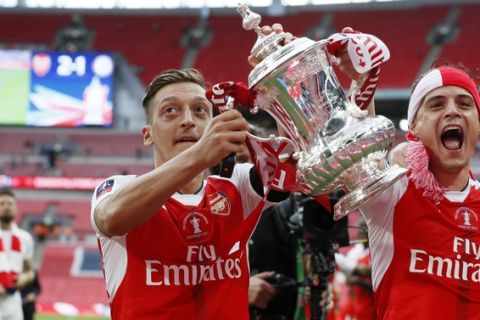Arsenal's Mesut Ozil, left, celebrates with the trophy after winning the English FA Cup final soccer match between Arsenal and Chelsea at Wembley stadium in London, Saturday, May 27, 2017. Arsenal won 2-1. (AP Photo/Kirsty Wigglesworth)