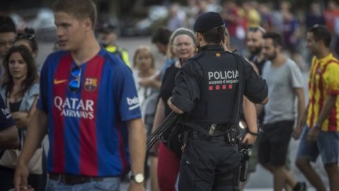 An armed police officer watches as fans walk towards the stadium before a La Liga soccer match between Barcelona and Betis at the Camp Nou stadium in Barcelona , Spain, Sunday, Aug. 20, 2017. Security was stepped up for the match after a terror attack that killed 14 people and wounded over 120 in Barcelona and police put up scores of roadblocks across northeast Spain on Sunday in hopes of capturing a fugitive suspect at large following the vehicle attack.(AP Photo/Santi Palacios)