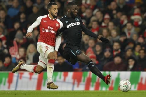 Arsenal's Theo Walcott, left, vies for the ball with West Ham United's Arthur Masuaku during the English League Cup quarterfinal soccer match between Arsenal and West Ham United at the Emirates stadium in London, Tuesday, Dec. 19, 2017. (AP Photo/Alastair Grant)
