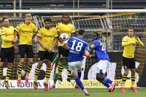 Schalke's Daniel Caligiuri, center, shoots a free kick during the German Bundesliga soccer match between Borussia Dortmund and Schalke 04 in Dortmund, Germany, Saturday, May 16, 2020. The German Bundesliga becomes the world's first major soccer league to resume after a two-month suspension because of the coronavirus pandemic. (AP Photo/Martin Meissner, Pool)