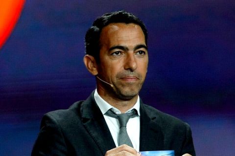 Former French forward Youri Djorkaeff shows the draw Internazional Milan, during the Europa League draw ceremony of the first round of the 2014/2015 Europa League, at the Grimaldi Forum in Monaco, Friday, Aug. 29, 2014. (AP Photo/Claude Paris)