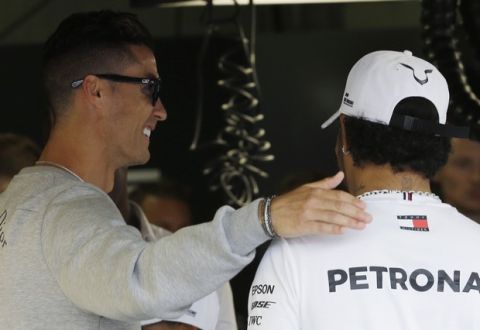 Cristiano Ronaldo, left, hugs with Mercedes driver Lewis Hamilton of Britain at the pit line ahead of the second practice session at the Monaco racetrack, in Monaco, Thursday, May 23, 2019. The Formula one race will be held on Sunday. (AP Photo/Luca Bruno)